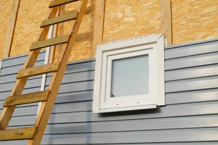 Ladder leaning on house with unfinished siding