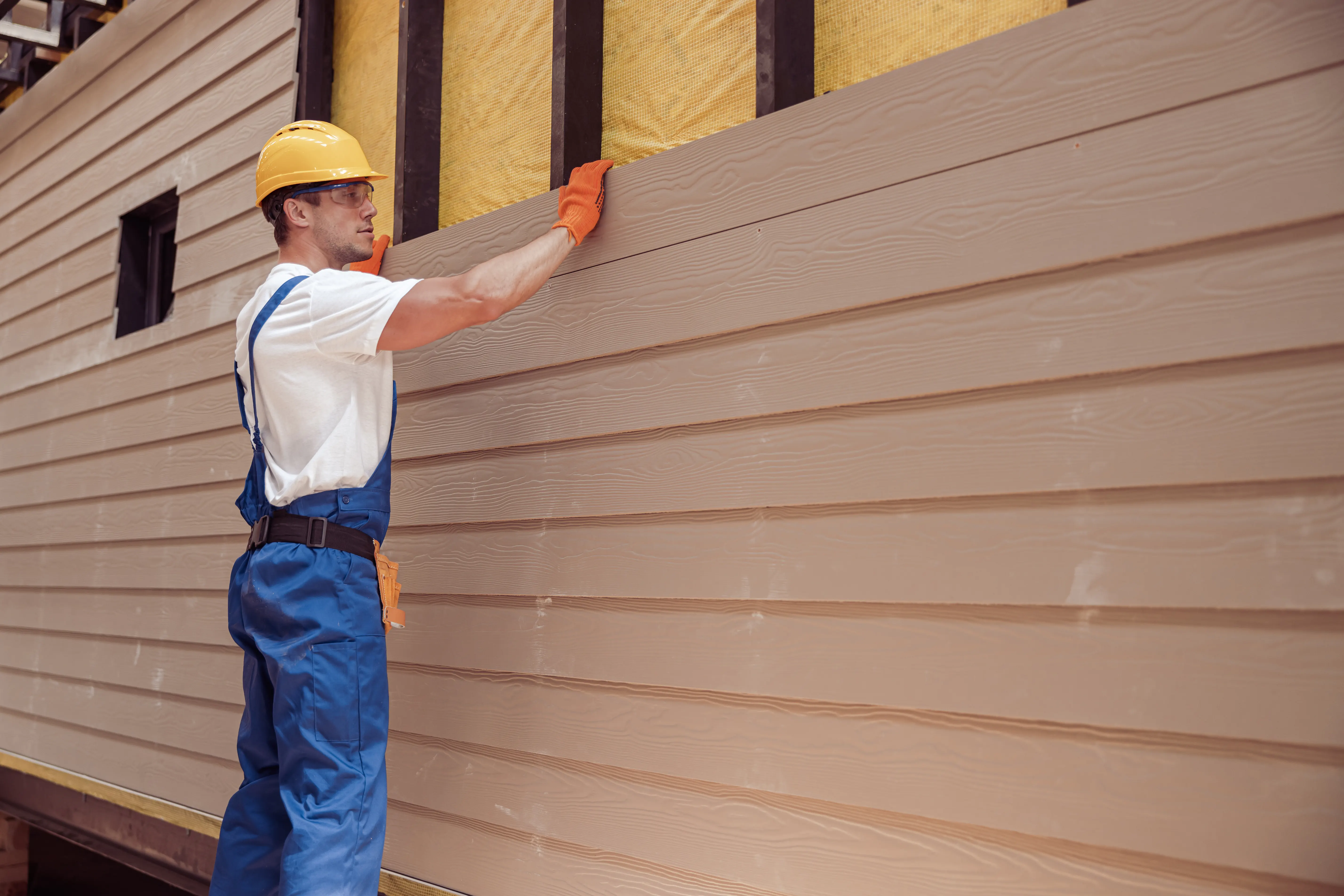 What Is Siding 11 A man attaching light siding to a house